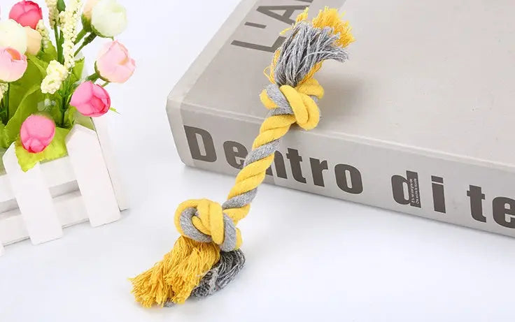 Rope pet toy made of cotton in yellow and gray on a book.