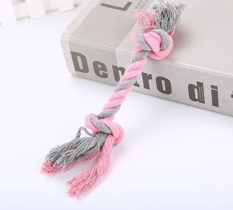 Pink and gray cotton rope pet toy on a book.