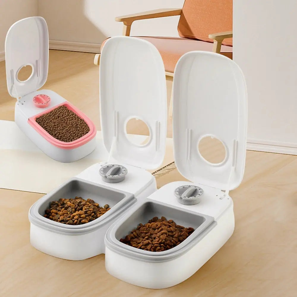 Automatic pet feeder with dual meal compartments, shown in pink and gray, designed for cats and dogs.